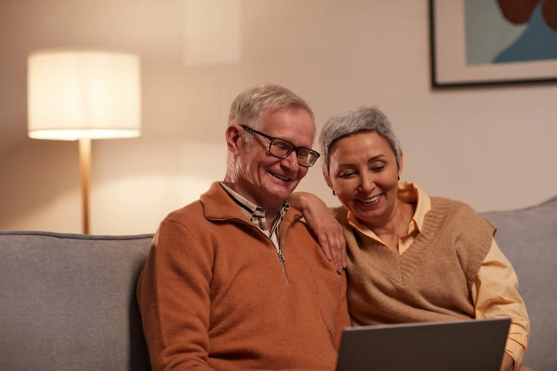 an and Woman Sitting on Sofa While Looking at a Laptop